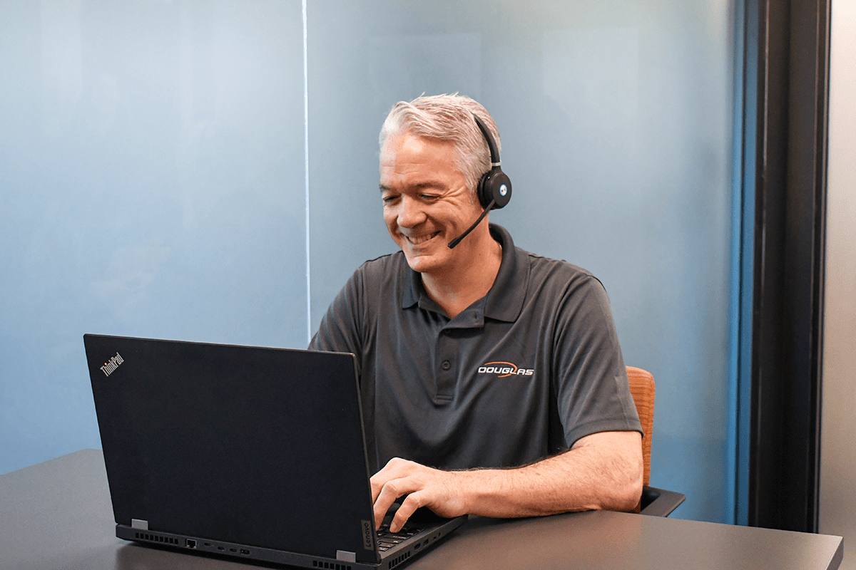 Douglas representative sitting at desk with laptop and headphones on a video call