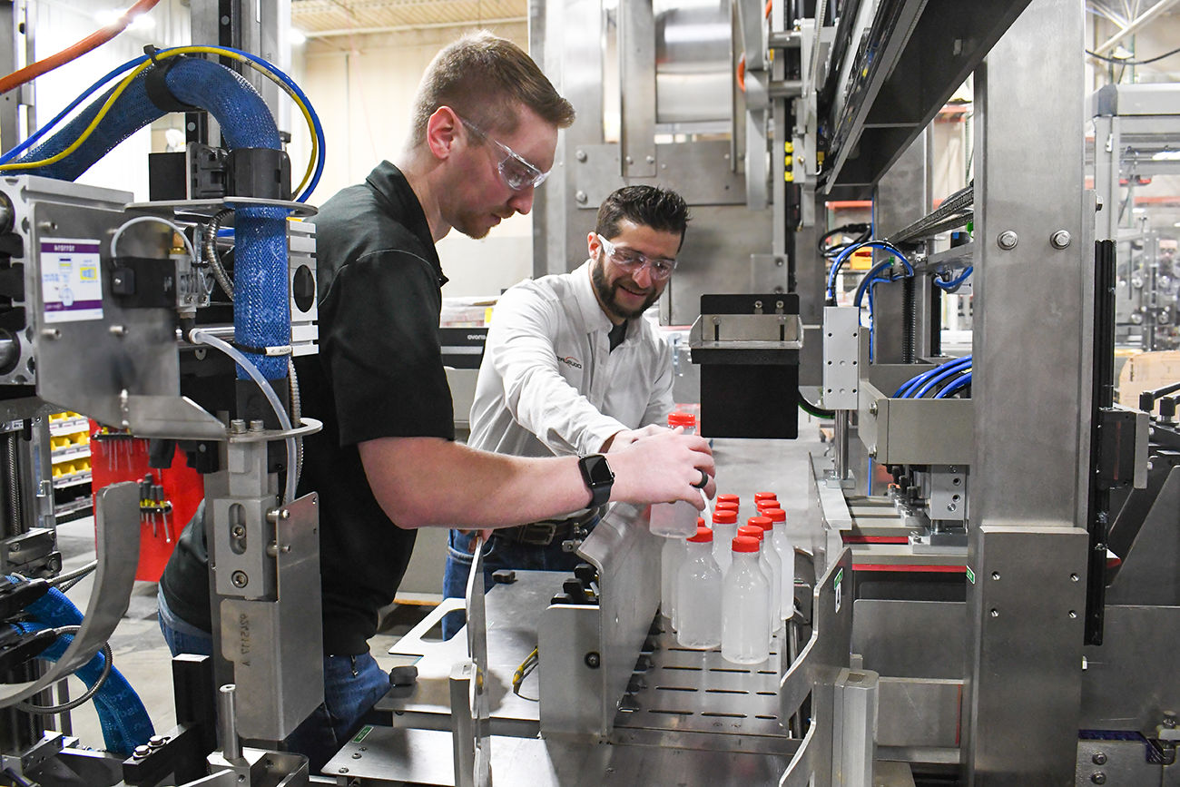 two operators lining up plastic bottles to test run in a machine