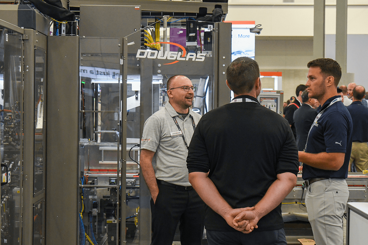 Group of people standing and having a conversation by a packaging machine