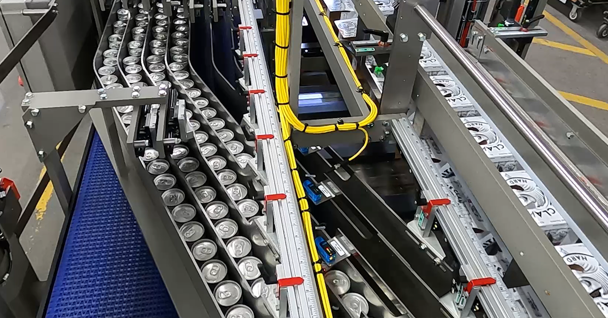 Beverage cans and paperboard cartons running through lanes on a multipacker machine